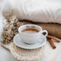 Biała filiżanka porcelanowa 250 ml ze spodkiem - motyw złotego serca z napisem Chłoń dobro dla bliskiej osoby na urodziny Filiżanka porcelanowa ze złotym sercem ze spodkiem - Chłoń dobro nadzwyczajnie.mom — widok z boku na białym tle